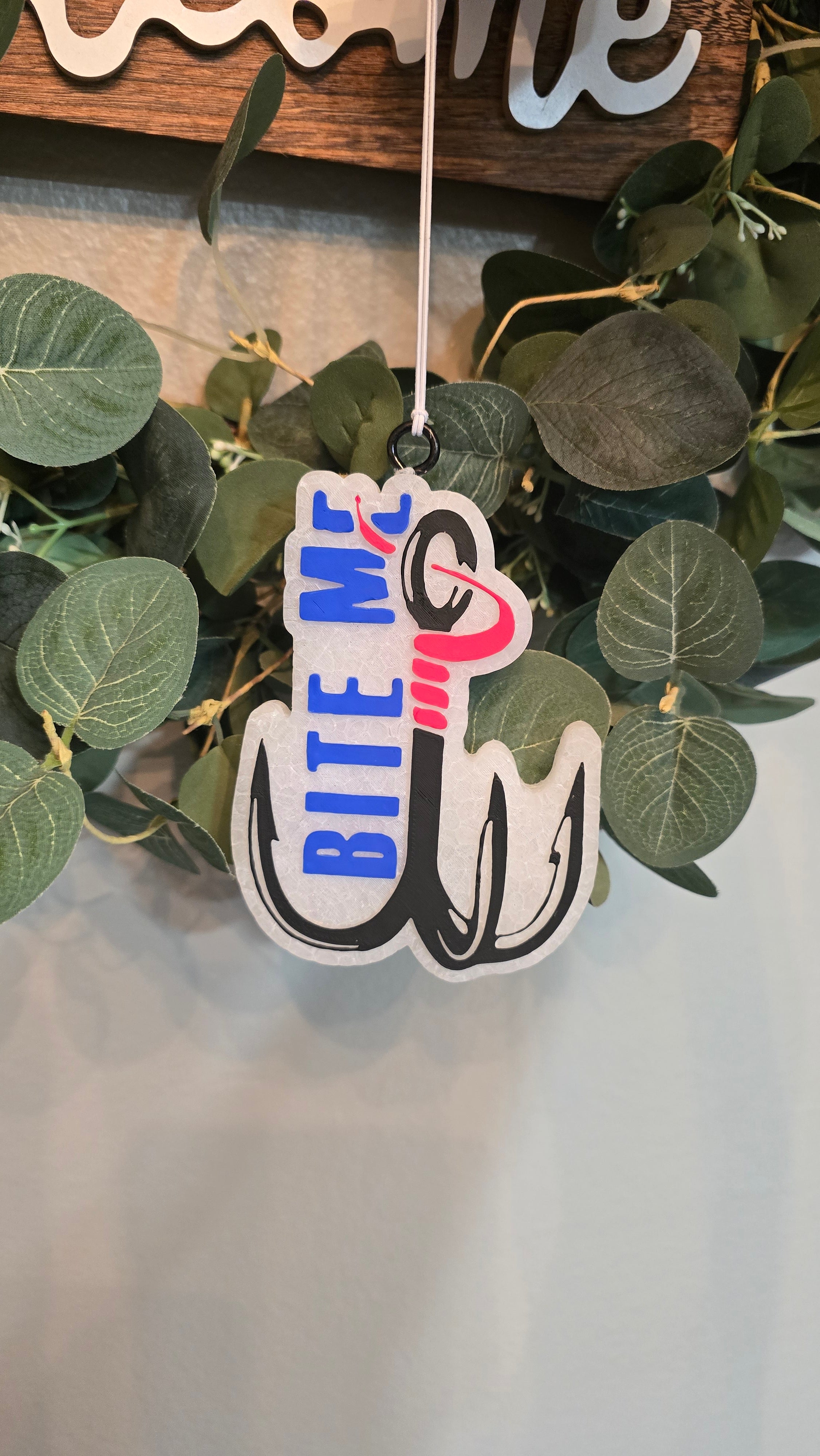 Handmade fishing hook-shaped car freshie featuring the phrase "Bite Me," designed as a fun scented rearview mirror accessory for fishing enthusiasts.