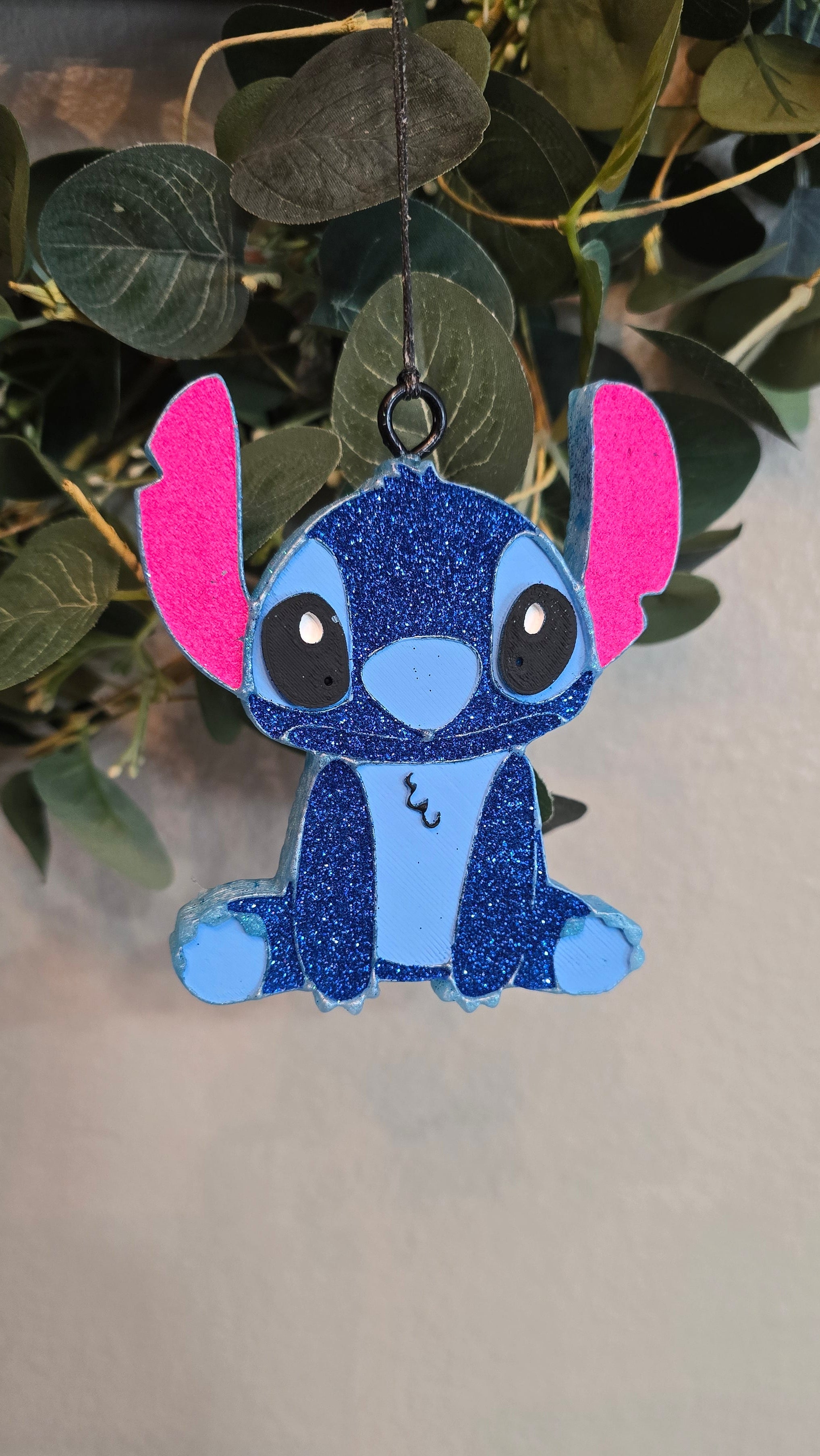 Blue glitter Stitch-inspired handmade car freshie with pink ears hanging from a rearview mirror.