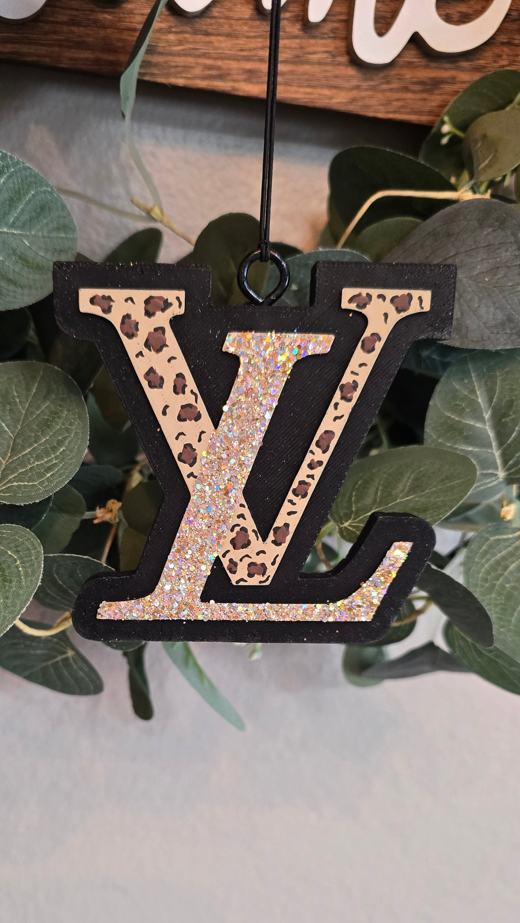 A black LV scented monogram car freshie hanging ornament with a leopard print and holographic glitter pattern