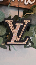 A black LV scented monogram car freshie hanging ornament with a leopard print and holographic glitter pattern